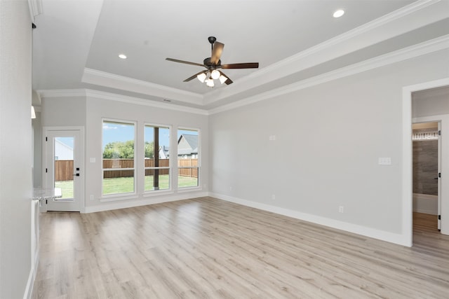 empty room with crown molding, ceiling fan, a tray ceiling, and light hardwood / wood-style flooring