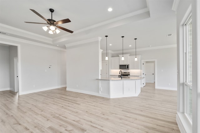 kitchen featuring light stone counters, white cabinets, hanging light fixtures, light hardwood / wood-style flooring, and crown molding