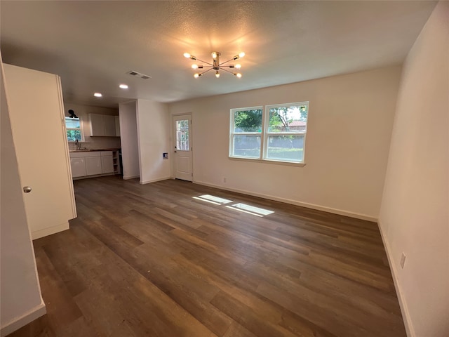 unfurnished living room featuring a chandelier, dark hardwood / wood-style floors, and sink