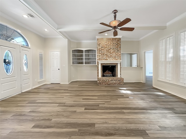 foyer entrance with crown molding, wood-type flooring, a brick fireplace, and ceiling fan