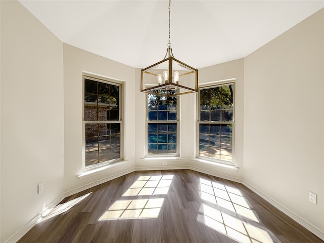 unfurnished dining area featuring a notable chandelier and dark hardwood / wood-style flooring