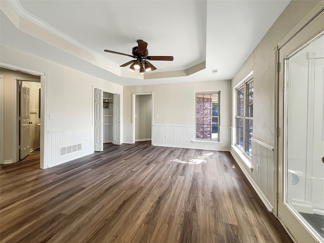 unfurnished bedroom with dark wood-type flooring, ceiling fan, a raised ceiling, and crown molding