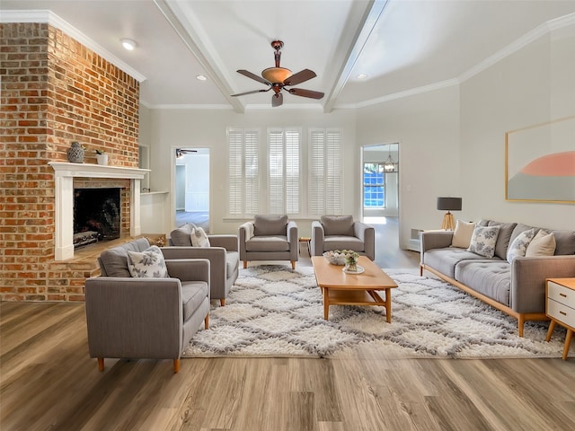 living room with hardwood / wood-style flooring, beam ceiling, crown molding, a fireplace, and ceiling fan