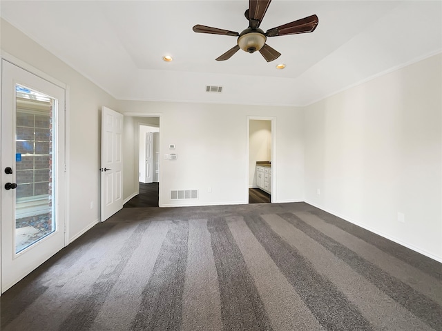 carpeted empty room featuring ceiling fan and a raised ceiling