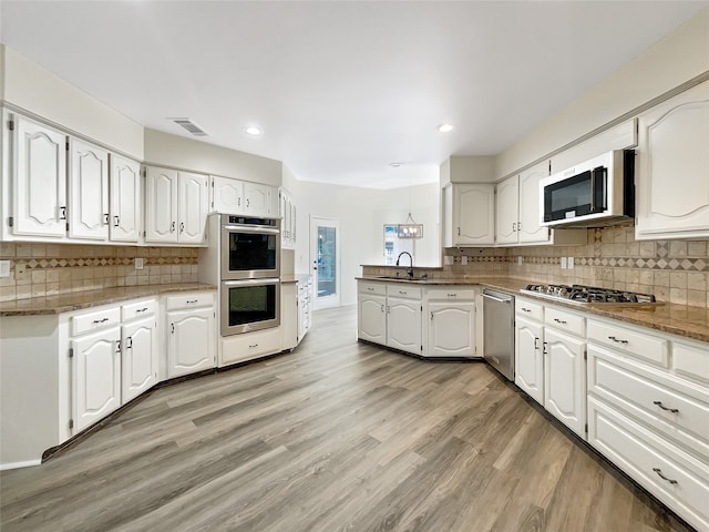 kitchen featuring stainless steel appliances, tasteful backsplash, light hardwood / wood-style flooring, and white cabinets