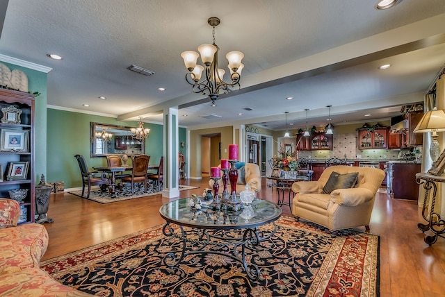 living room with light hardwood / wood-style floors, an inviting chandelier, crown molding, and a textured ceiling