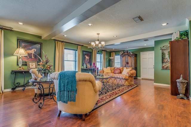 living room with hardwood / wood-style flooring, a textured ceiling, a chandelier, and beamed ceiling