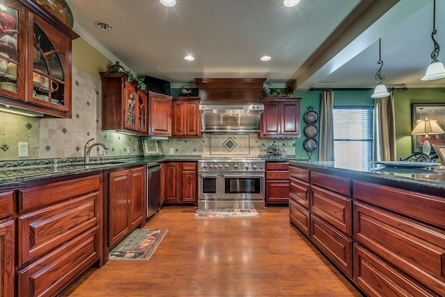 kitchen with dark stone countertops, tasteful backsplash, light wood-type flooring, pendant lighting, and appliances with stainless steel finishes