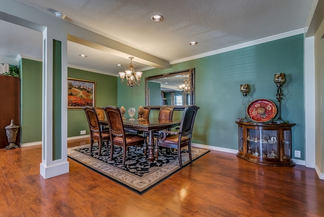 dining area with wood-type flooring, a textured ceiling, a chandelier, and ornamental molding