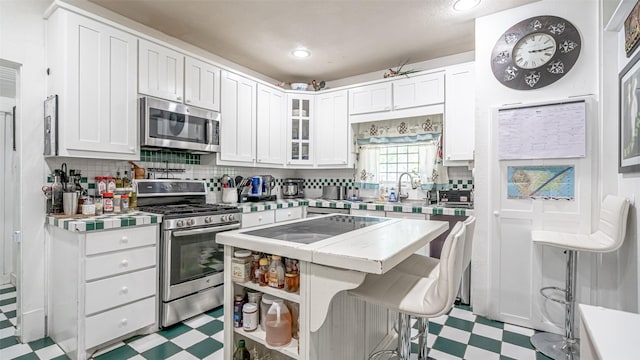 kitchen featuring white cabinets, a breakfast bar, stainless steel appliances, and tasteful backsplash