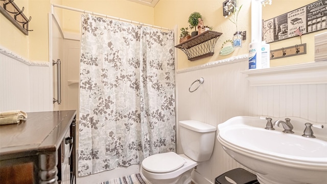 bathroom featuring toilet, walk in shower, wood walls, and sink