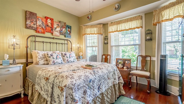 bedroom with multiple windows and dark wood-type flooring