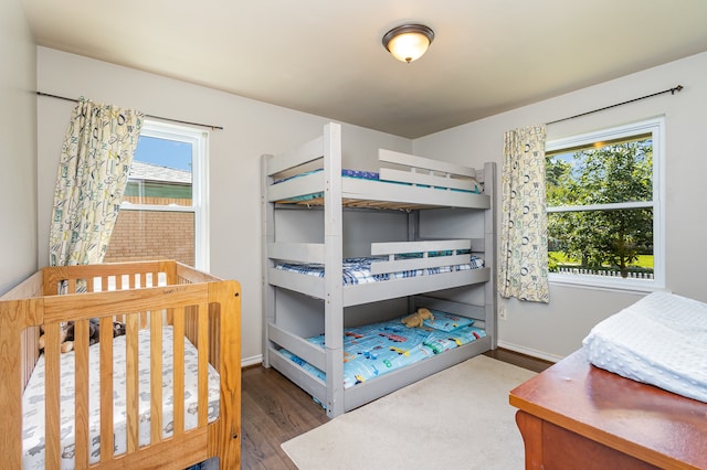 bedroom with hardwood / wood-style flooring, a nursery area, and multiple windows