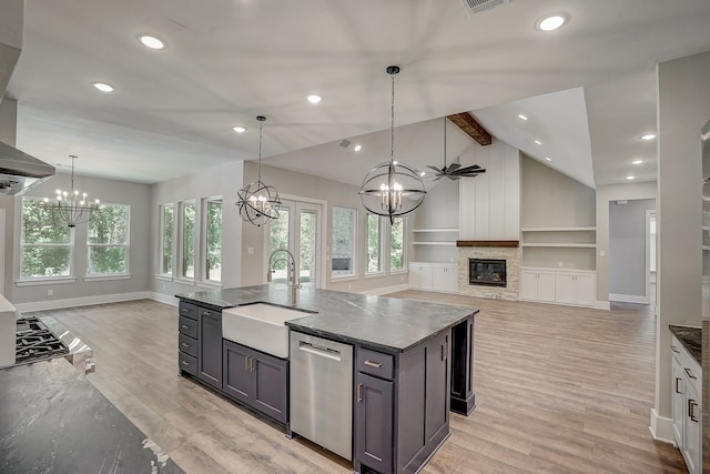 kitchen featuring light hardwood / wood-style floors, stainless steel dishwasher, an island with sink, a fireplace, and sink