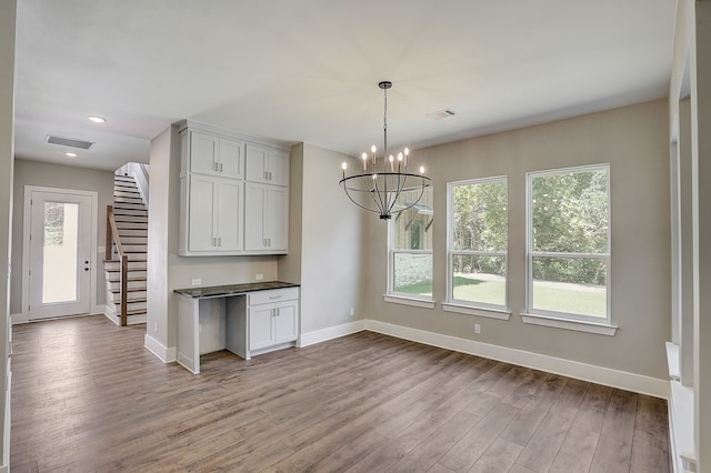 unfurnished dining area with a wealth of natural light, wood-type flooring, and a notable chandelier