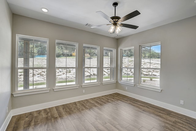 empty room with plenty of natural light, ceiling fan, and dark hardwood / wood-style floors