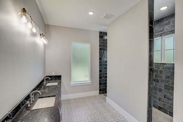 bathroom with tile flooring, tiled shower, and double vanity