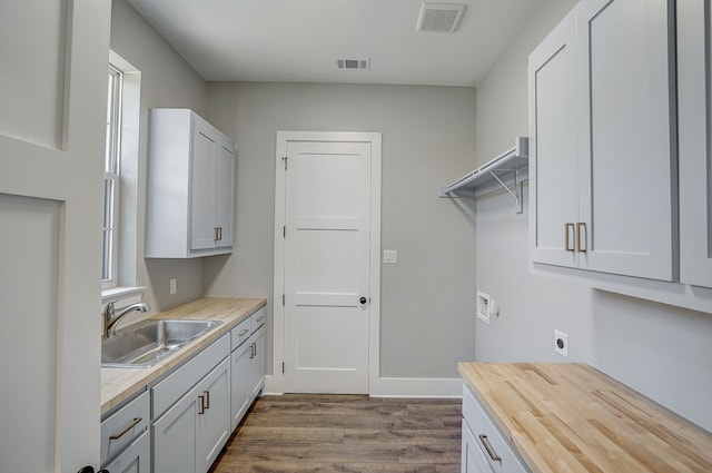 washroom with cabinets, washer hookup, electric dryer hookup, hardwood / wood-style floors, and sink