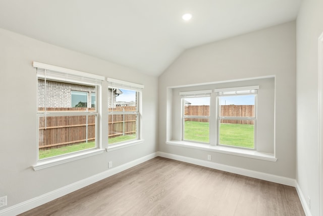 unfurnished room with wood-type flooring, vaulted ceiling, and a healthy amount of sunlight