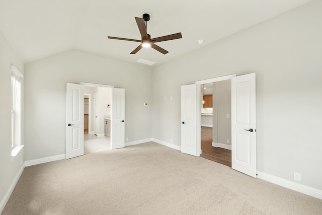 unfurnished bedroom with ensuite bath, vaulted ceiling, light carpet, and ceiling fan