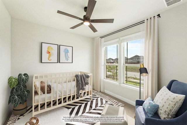 bedroom featuring carpet, ceiling fan, multiple windows, and a crib