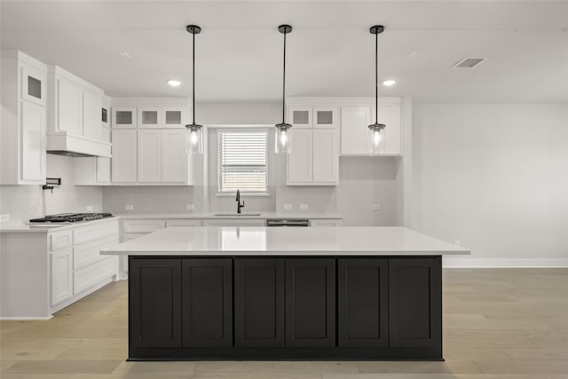 kitchen with light wood-type flooring, a center island, white cabinetry, and sink