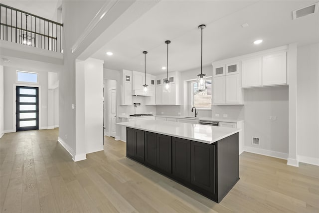 kitchen featuring a kitchen island, a healthy amount of sunlight, light wood-type flooring, and white cabinets