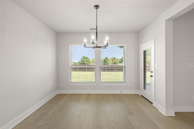 unfurnished dining area with an inviting chandelier and light hardwood / wood-style floors