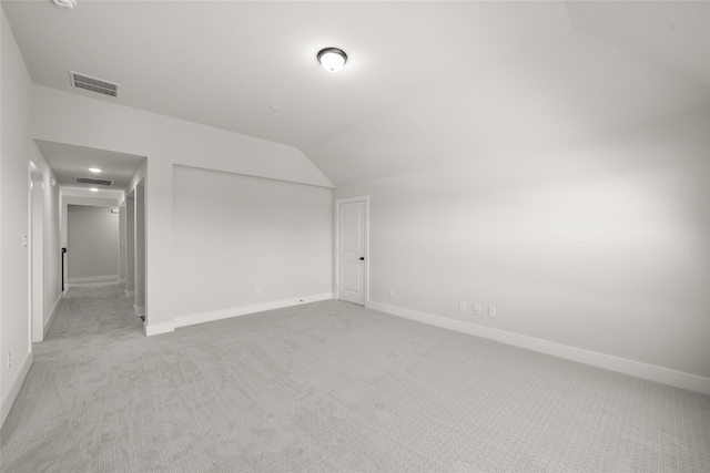 carpeted empty room featuring vaulted ceiling