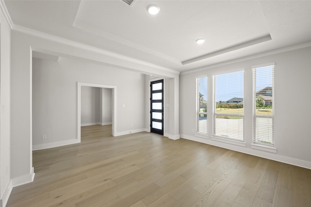 unfurnished room with ornamental molding, a tray ceiling, and light hardwood / wood-style floors