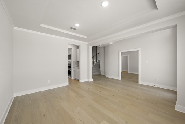 spare room with ornamental molding, light hardwood / wood-style flooring, and a raised ceiling