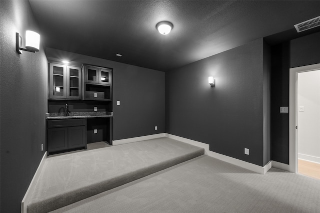 home theater room featuring light colored carpet, a textured ceiling, and sink