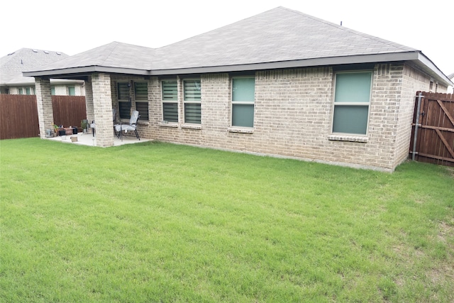 rear view of property featuring a lawn and a patio area