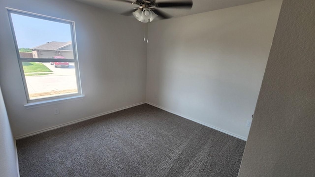 spare room featuring ceiling fan and dark colored carpet