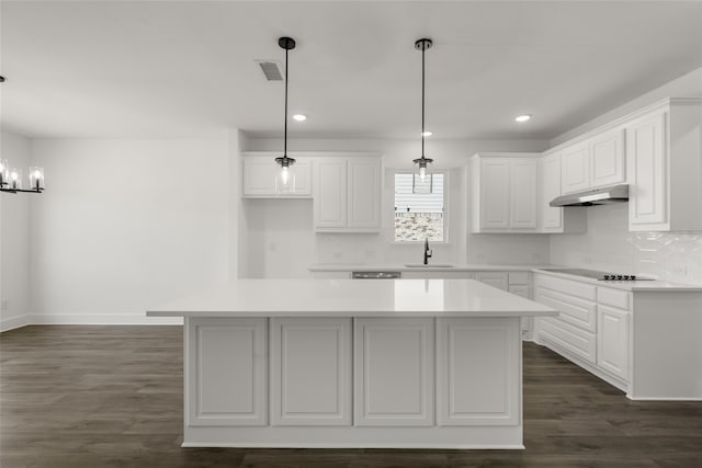 kitchen with dark hardwood / wood-style flooring, a kitchen island, sink, hanging light fixtures, and white cabinets