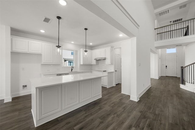 kitchen featuring dark hardwood / wood-style floors, decorative light fixtures, a center island, sink, and white cabinets