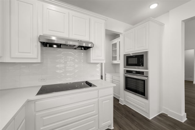 kitchen with ventilation hood, white cabinetry, black appliances, dark wood-type flooring, and tasteful backsplash