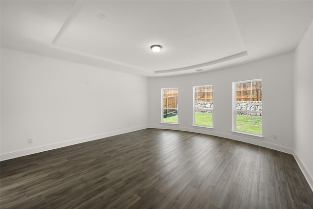 empty room with a tray ceiling and dark wood-type flooring