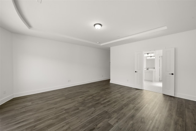 spare room with dark hardwood / wood-style floors and a raised ceiling