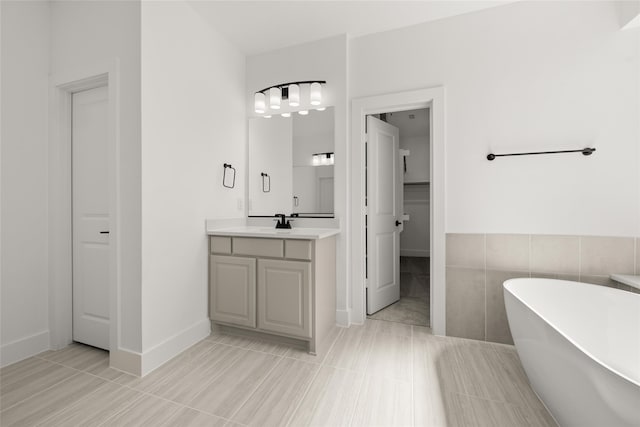 bathroom with vanity, a bath, and tile walls