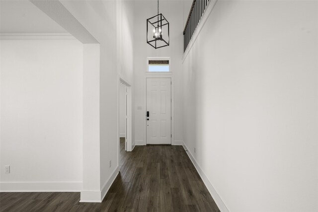 corridor featuring a high ceiling, dark hardwood / wood-style flooring, and a notable chandelier