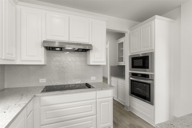 kitchen featuring light stone counters, black appliances, tasteful backsplash, light hardwood / wood-style floors, and white cabinetry