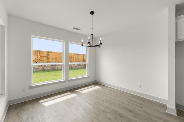 unfurnished dining area with light wood-type flooring and a notable chandelier