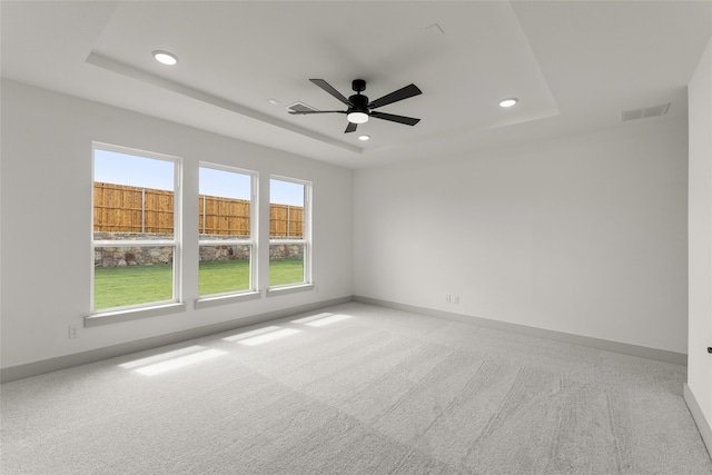 empty room featuring ceiling fan, a tray ceiling, and carpet flooring