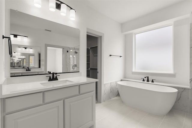 bathroom featuring tile patterned flooring, separate shower and tub, vanity, and tile walls