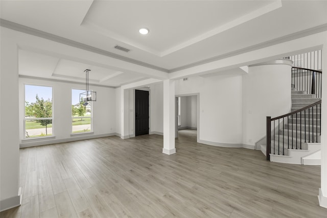 unfurnished living room with a tray ceiling, hardwood / wood-style floors, and an inviting chandelier