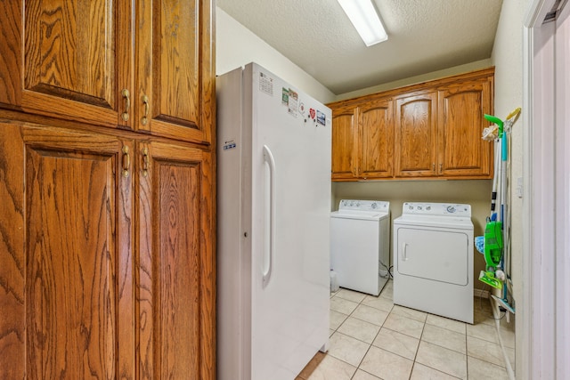 washroom with cabinets, a textured ceiling, independent washer and dryer, and light tile flooring