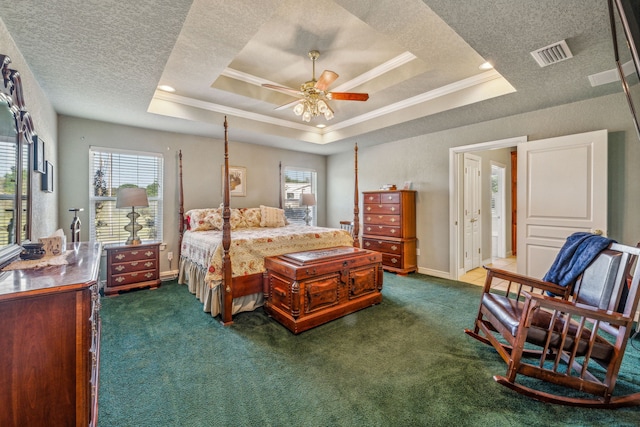 carpeted bedroom featuring a textured ceiling, ceiling fan, and a raised ceiling