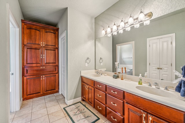 bathroom featuring dual vanity, tile flooring, and a textured ceiling