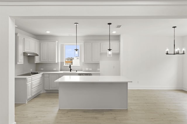 kitchen with sink, black electric stovetop, white cabinets, a kitchen island, and decorative backsplash